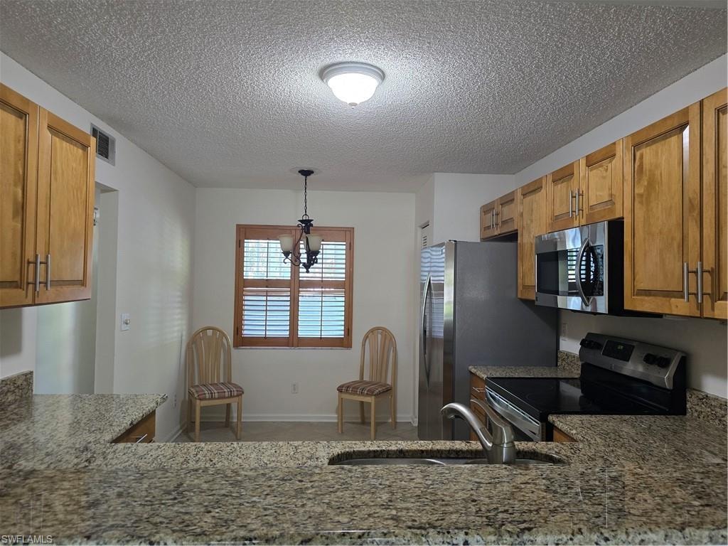 Granite countertops, wood cabinetry, stainless steel appliances, and a kitchen sink with a gooseneck faucet