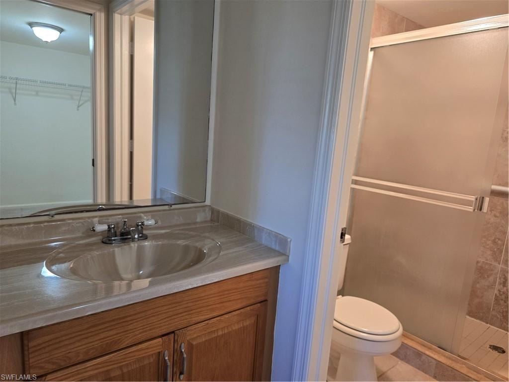 Vanity with integrated sink, wood-finish cabinetry, full-width mirror, and a shower enclosure with frosted glass