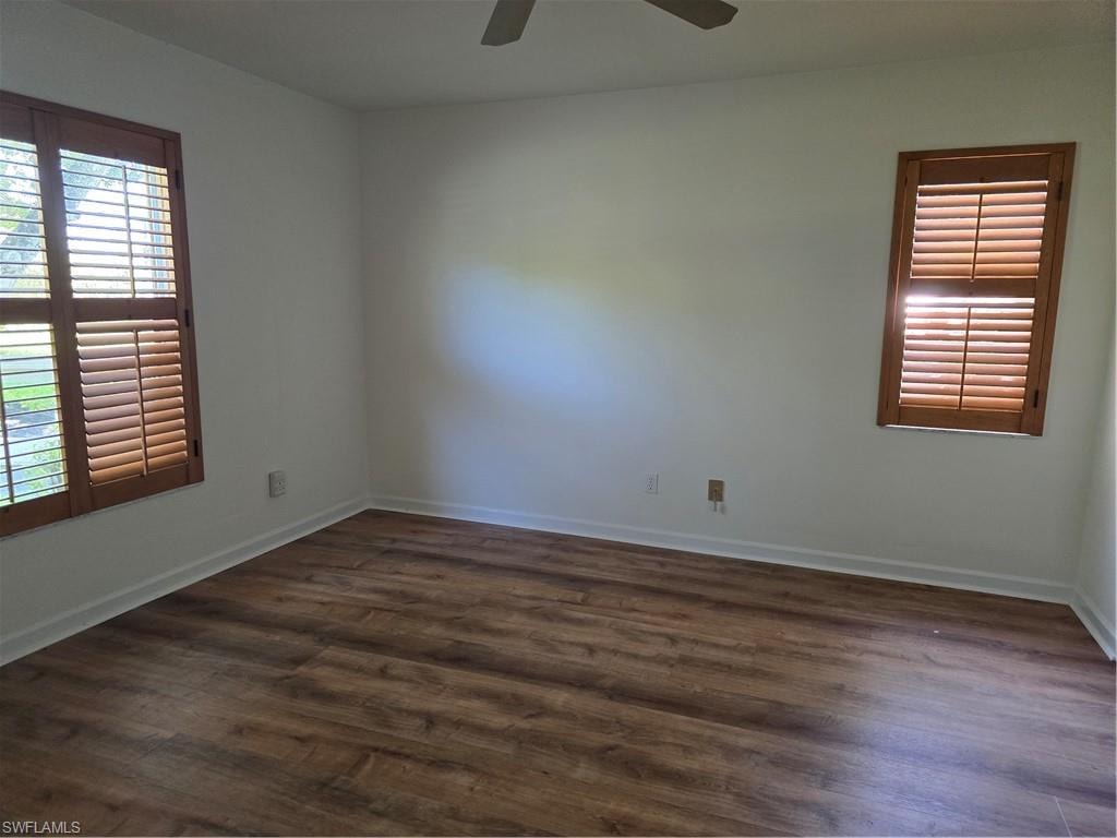 Wood-finish flooring, white walls, two windows with wood plantation shutters, and a ceiling fan