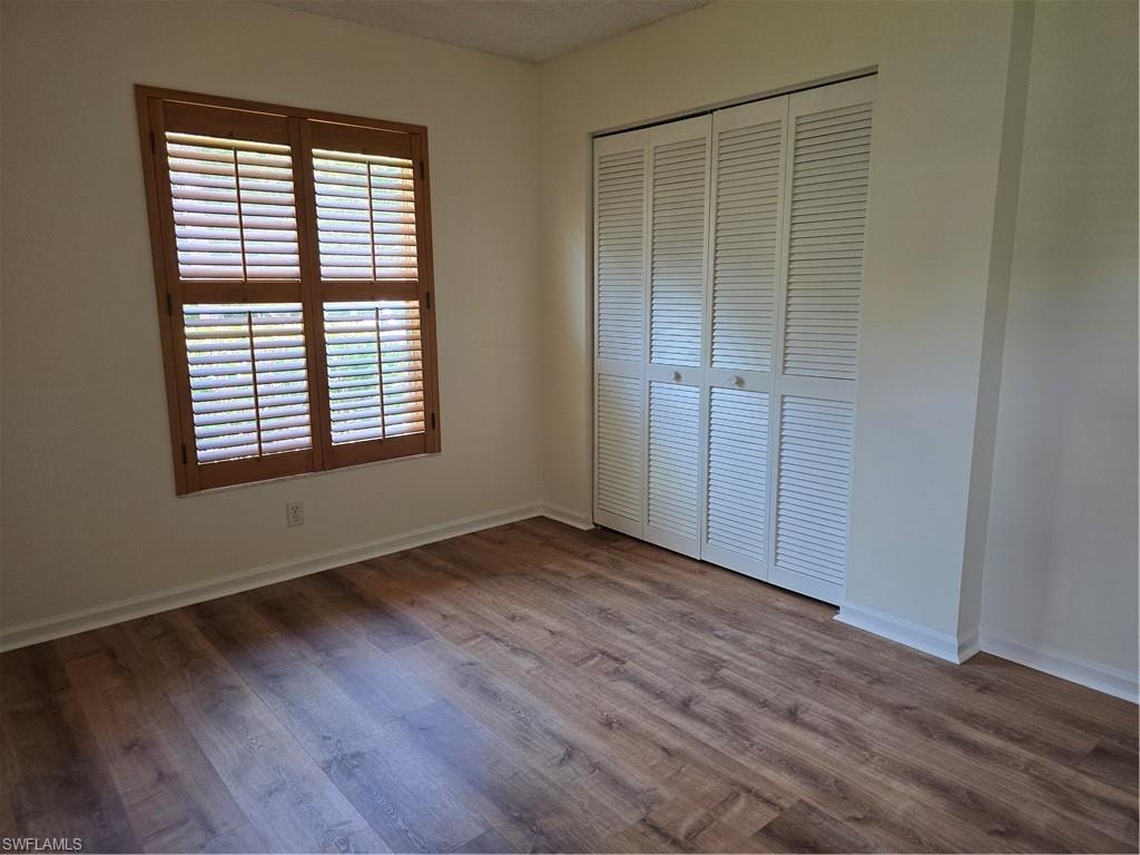 Wood-finish flooring, white walls, wood window shutters, and louvered bi-fold closet doors