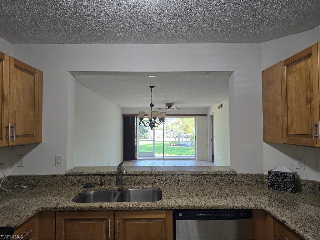 Kitchen featuring wood cabinetry, a stainless steel sink, and speckled stone countertops