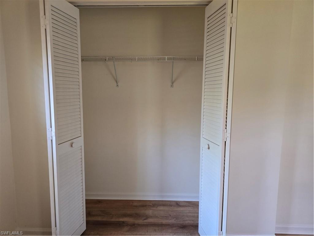 Louvered bi-fold doors enclosing a closet with wire shelving and wood-finish flooring