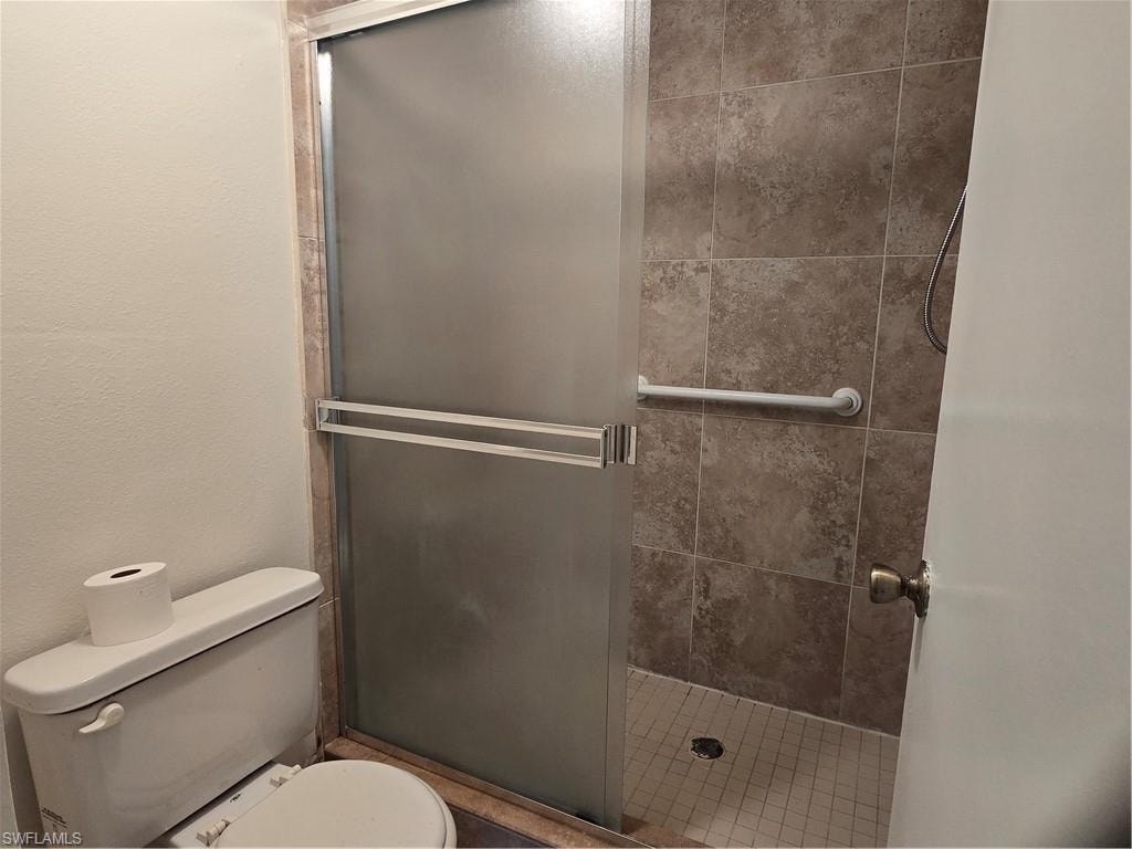 Shower enclosure featuring a frosted glass door, grab bar, and tiled surround