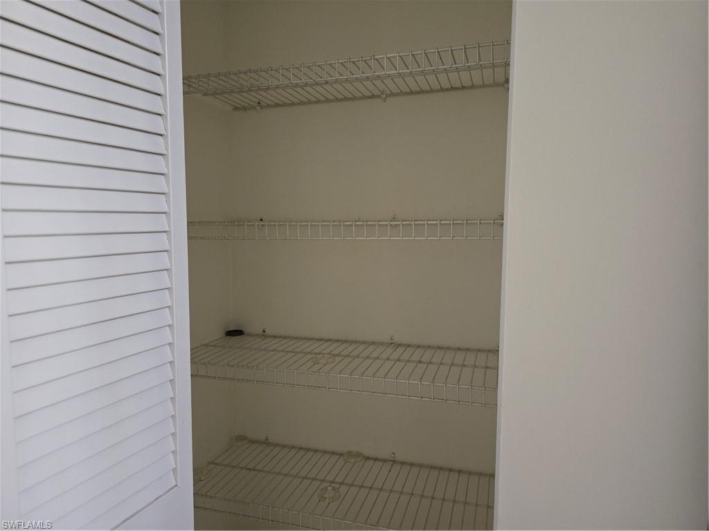 White louvered door opening to a pantry with multiple wire shelves