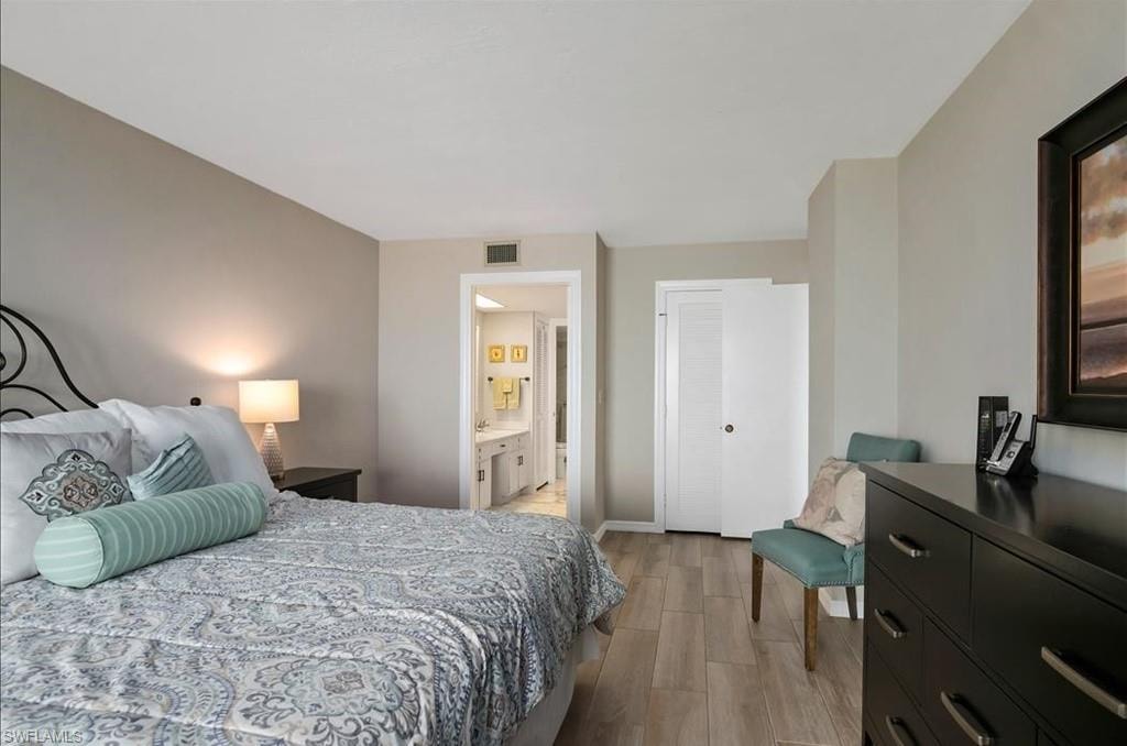 Bedroom with light wood-style flooring and ensuite bathroom