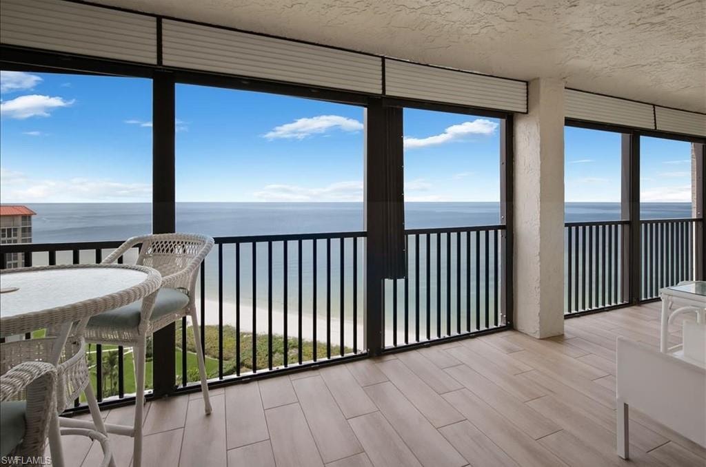 Sunroom / solarium with a water view, wood finish floors, and expansive windows