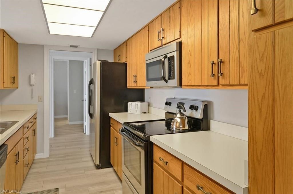 Kitchen with stainless steel appliances, light wood-type flooring, and light countertops