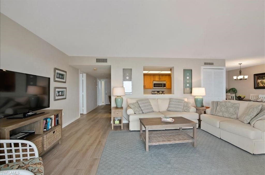 Living room with light wood-type flooring and a chandelier