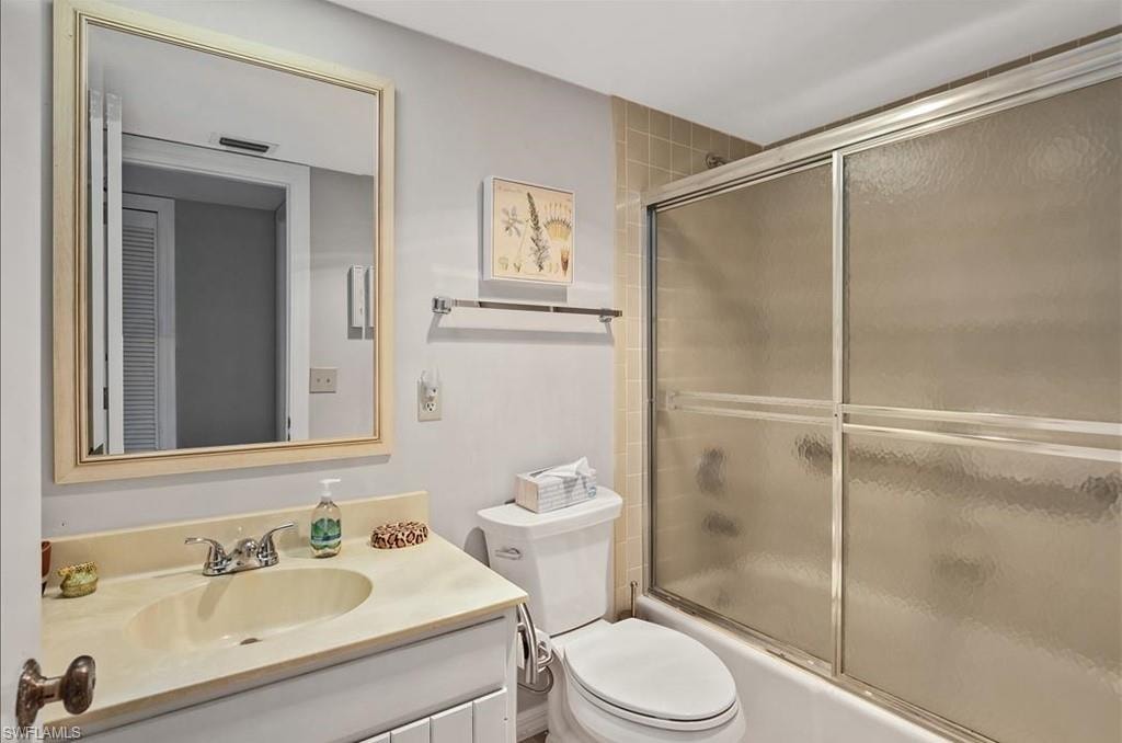 Bathroom with vanity and bath / shower combo with glass door
