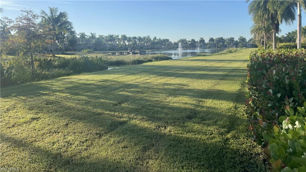 View of grassy yard featuring a water view and view of wooded area