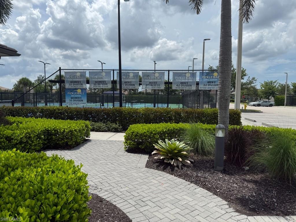 VERY ACTIVE Tennis Programs!  Paved pathway with mature landscaping, leading to pickleball courts featuring perimeter fencing and overhead lighting
