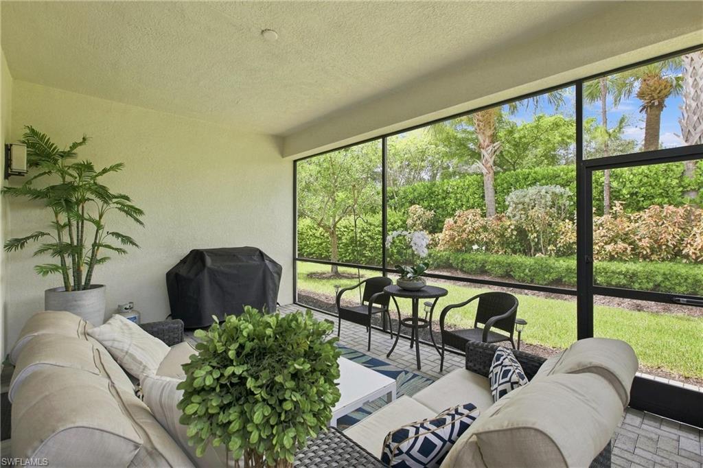 Screened outdoor living area with a textured ceiling, exterior wall sconce, paver flooring, and landscaped perimeter