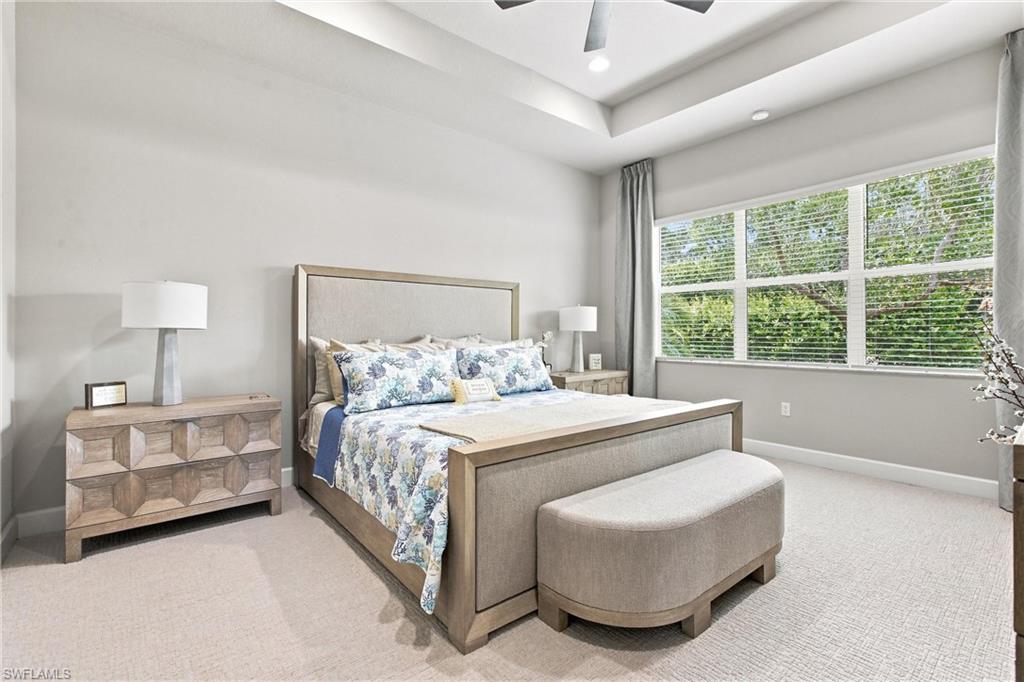 Recessed lighting, tray ceiling, carpet flooring, multiple large windows, and a ceiling fan