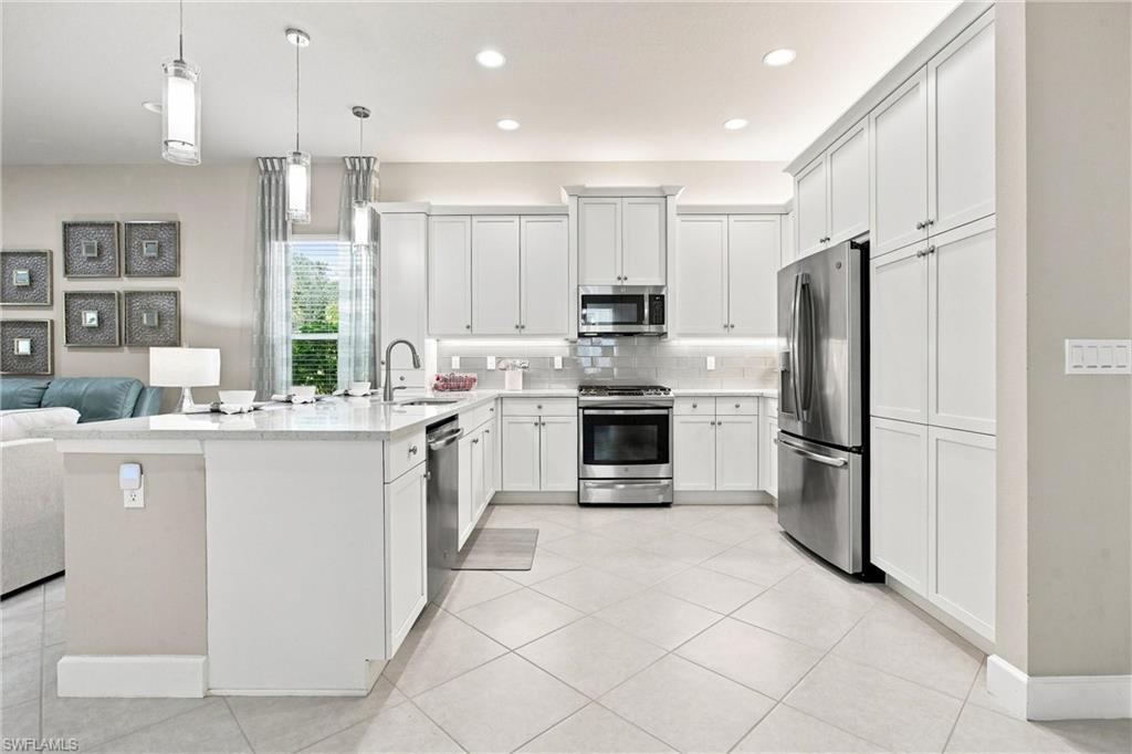 Kitchen with white cabinetry, stainless steel appliances, a center island with sink, tile flooring, and recessed lighting