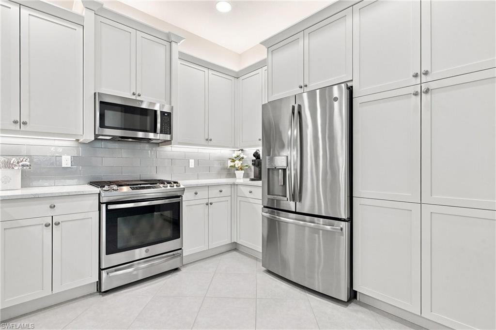 White shaker cabinetry, stainless steel appliances, subway tile backsplash, white countertops, and recessed lighting