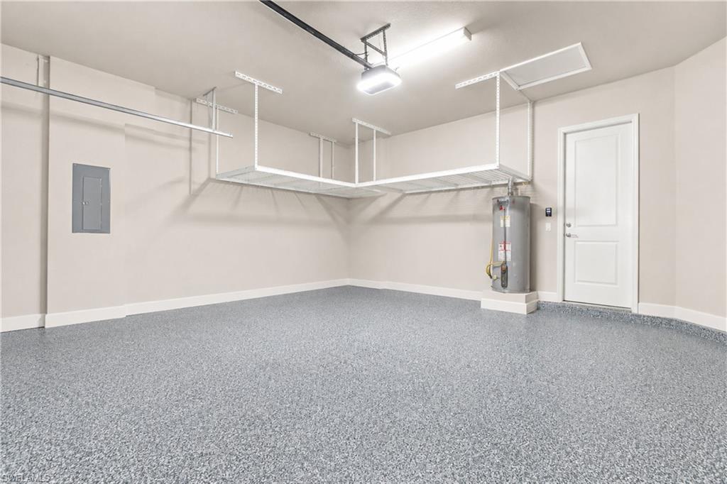 Garage featuring epoxy flooring, built-in overhead storage, and a white panel door