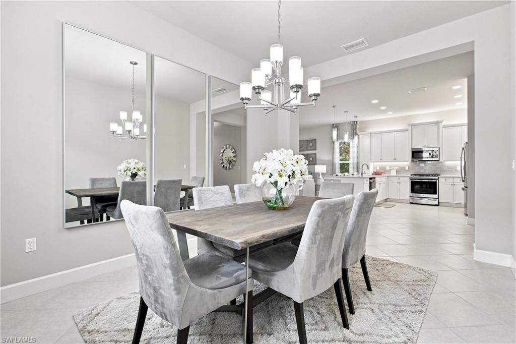 Open concept dining area with tile flooring, featuring a chandelier and recessed lighting