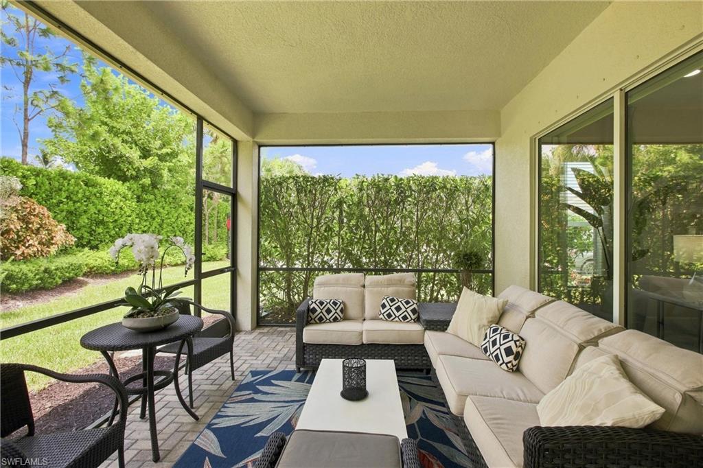 Screened patio featuring paver flooring, abundant natural light, and green landscaping
