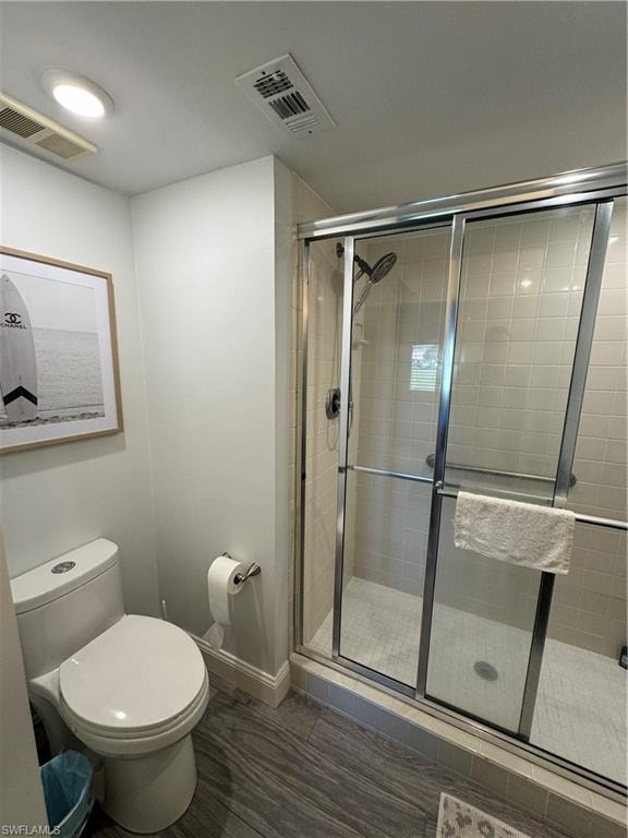 Walk-in shower with clear glass enclosure, white square tile surround, and gray wood-finish flooring