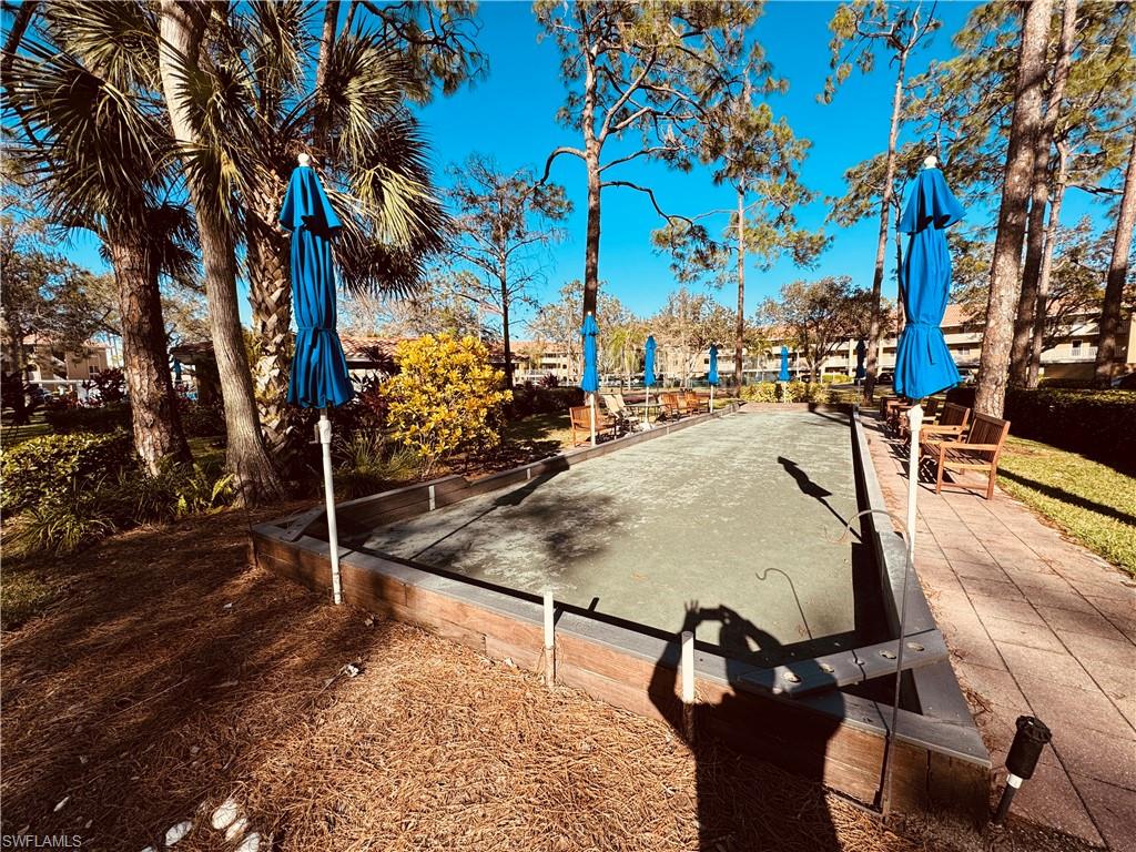 Bocce court with a paved walkway, surrounded by mature trees, and landscaping