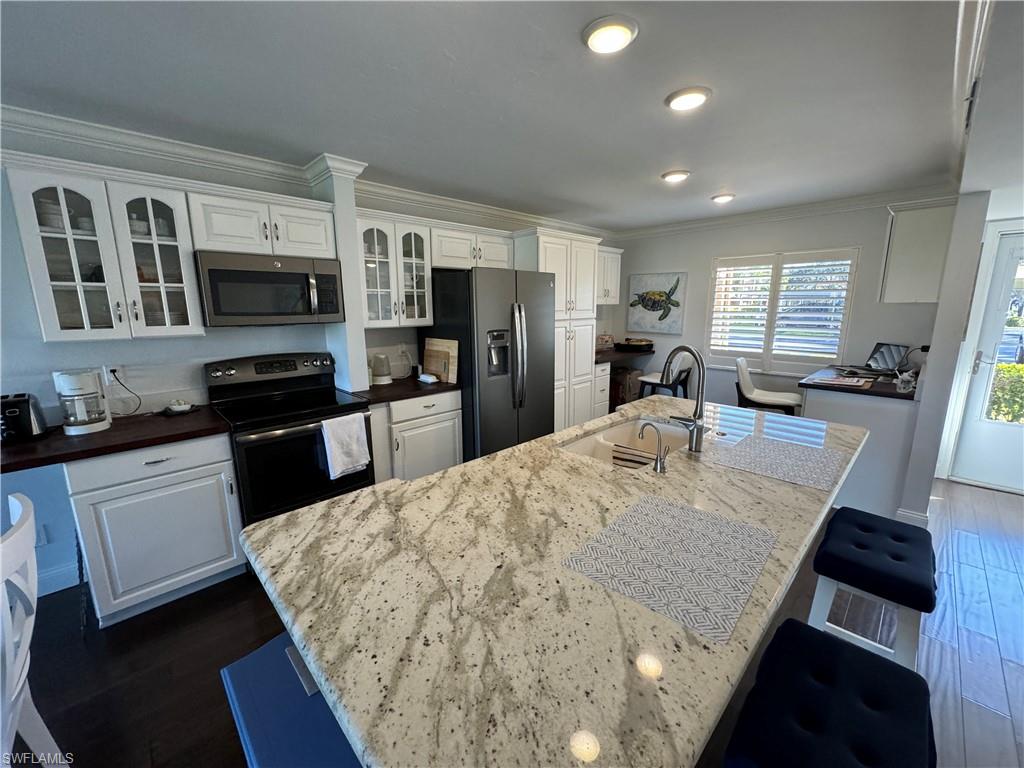 Kitchen featuring white cabinetry, stainless steel appliances, a large island with a composite countertop, and recessed lighting