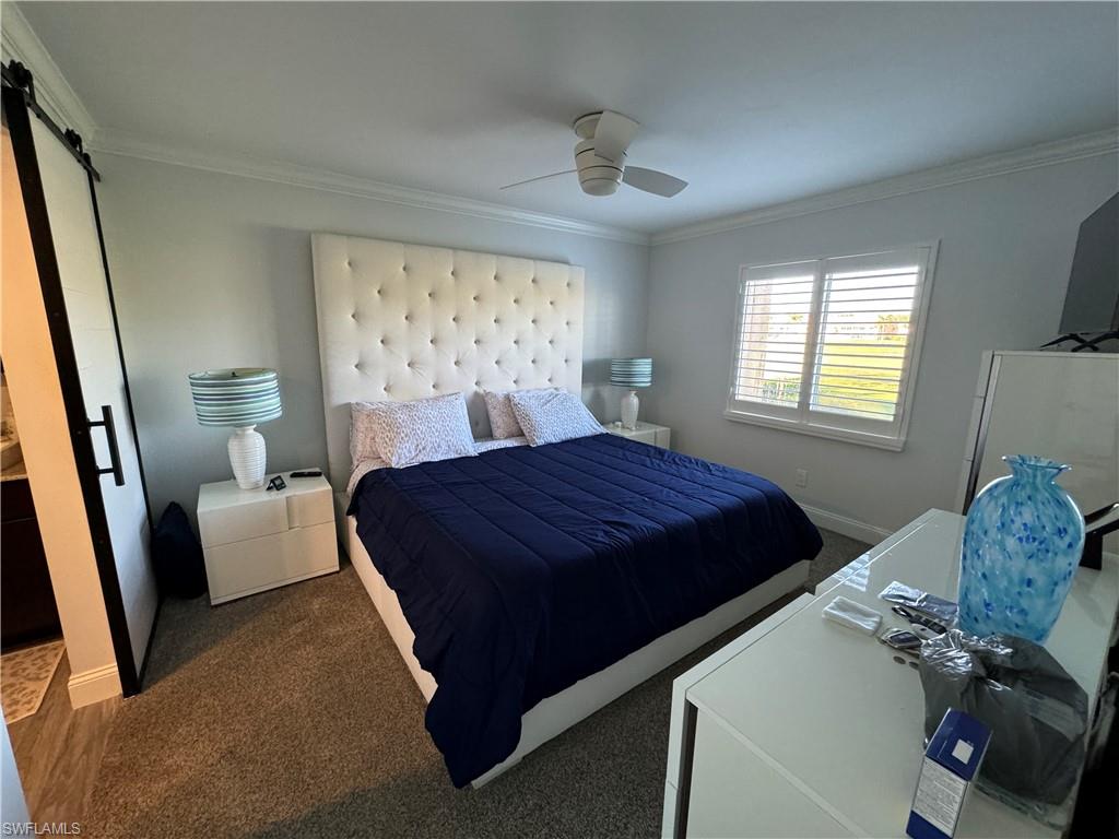 White tufted headboard, plantation shutters, crown molding, ceiling fan, and wood-finish flooring