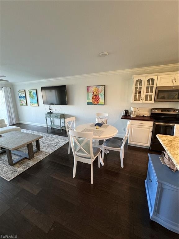 Dark wood-finish flooring extending throughout, white crown molding, recessed lighting, and kitchen cabinetry with glass panel doors