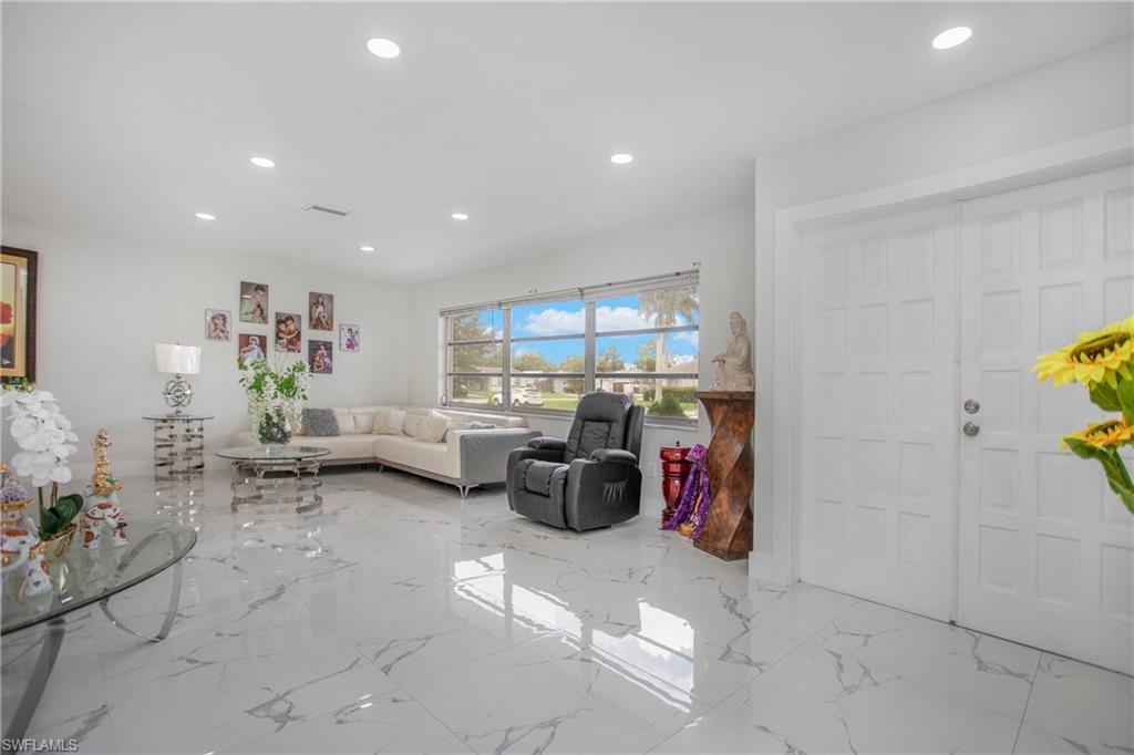Bright interior with recessed lighting, large windows, white walls, and polished tile flooring