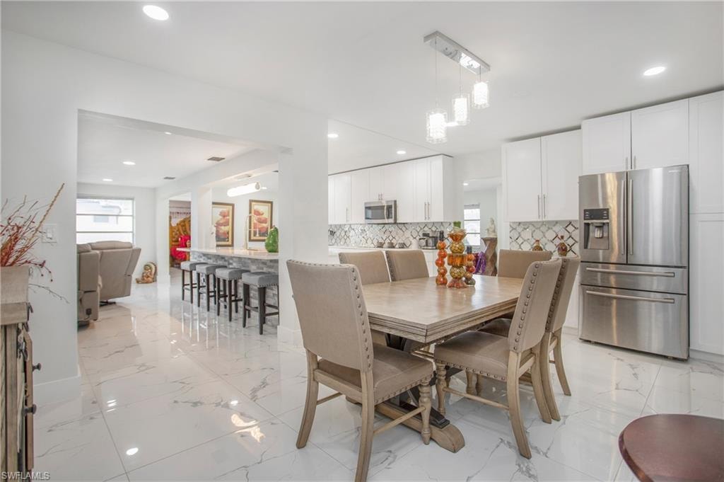 White cabinetry, stainless steel appliances, recessed lighting, and a patterned tile backsplash