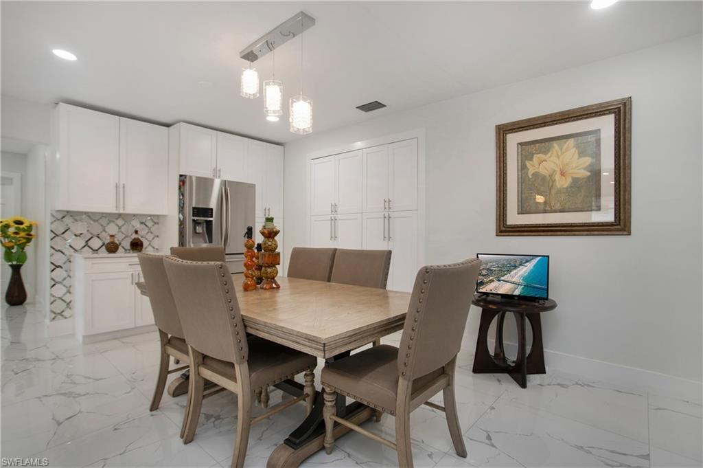 White cabinetry with stainless steel refrigerator, patterned tile backsplash, and recessed lighting
