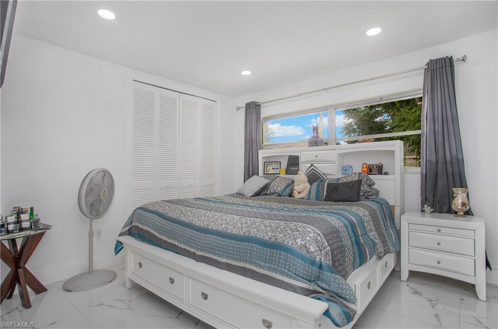 Recessed lighting, louvered bi-fold closet doors, large window, and white tile flooring