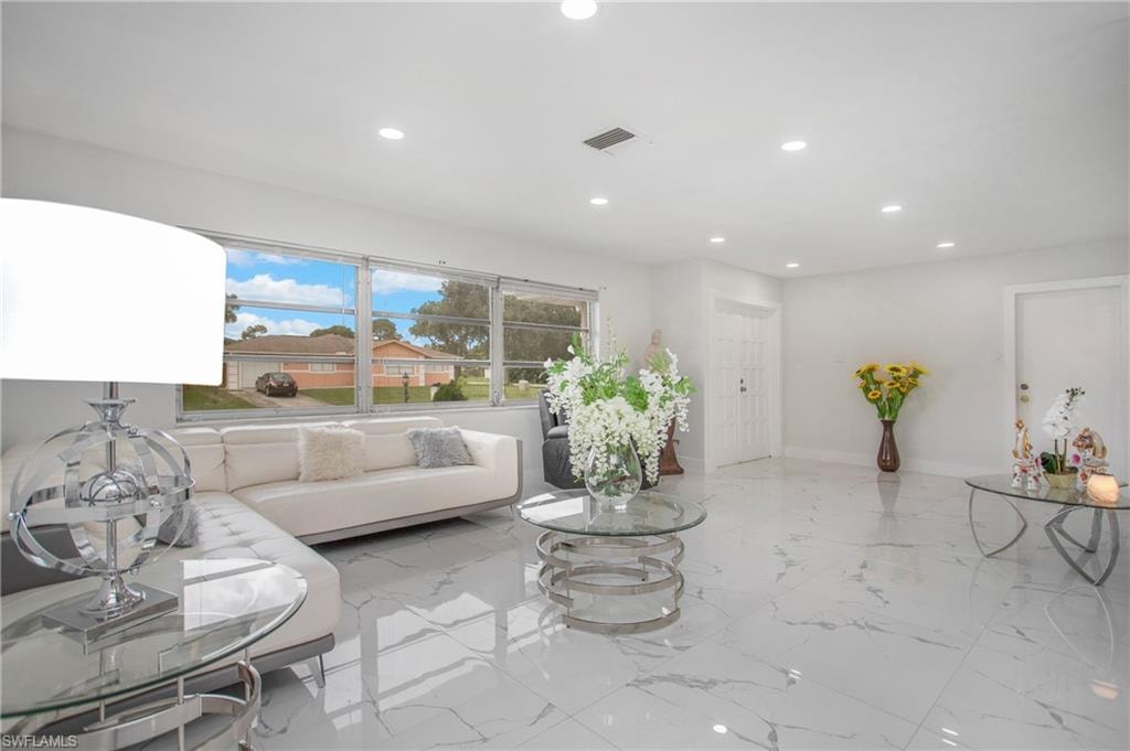 Spacious living area featuring polished tile flooring, recessed lighting, and a large window providing abundant natural light
