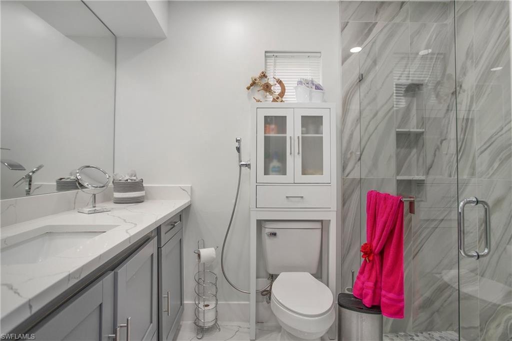 Vanity with a single undermount sink, a polished countertop, and gray shaker cabinetry