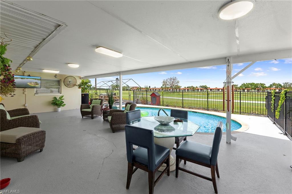 Covered patio with a concrete surface, featuring an inground pool and black perimeter fencing
