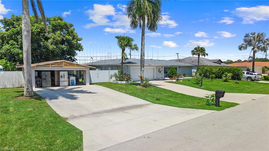Property exterior featuring a concrete driveway, attached two-car garage, separate carport, and mature palm trees