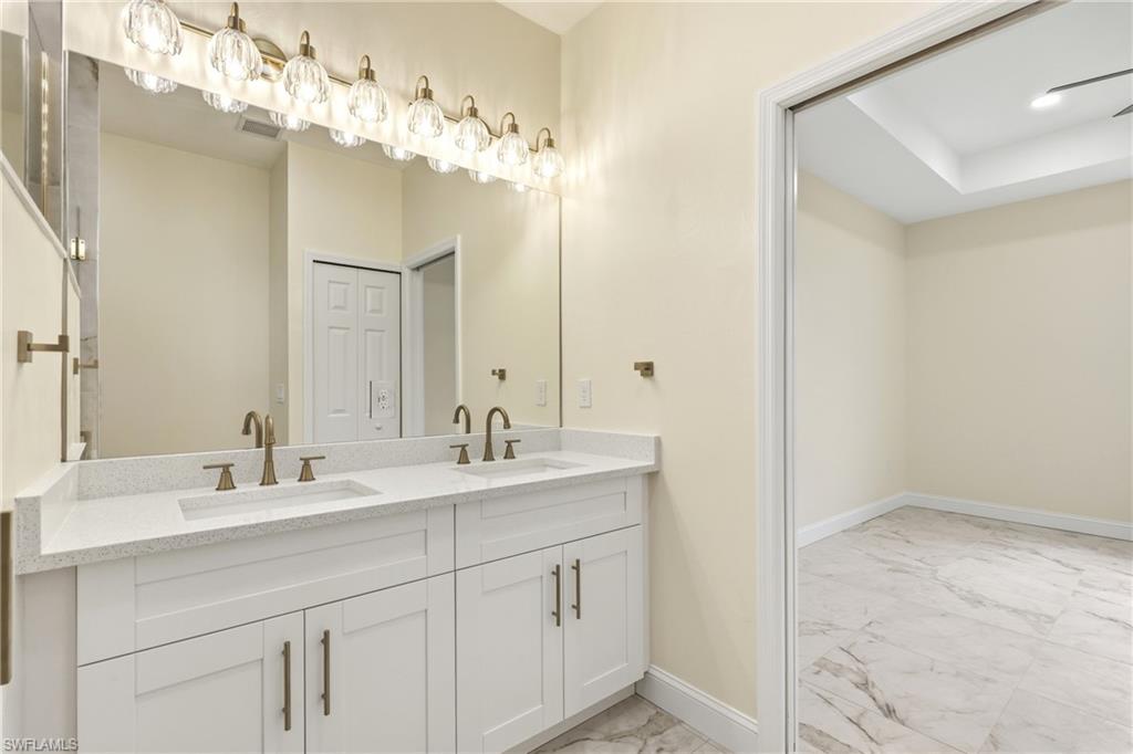 Double vanity with white cabinetry, integrated sinks, white speckled countertop, and bronze-finish faucets