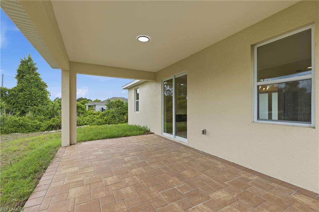 Covered patio with recessed lighting, complemented by a paver surface and sliding glass door access