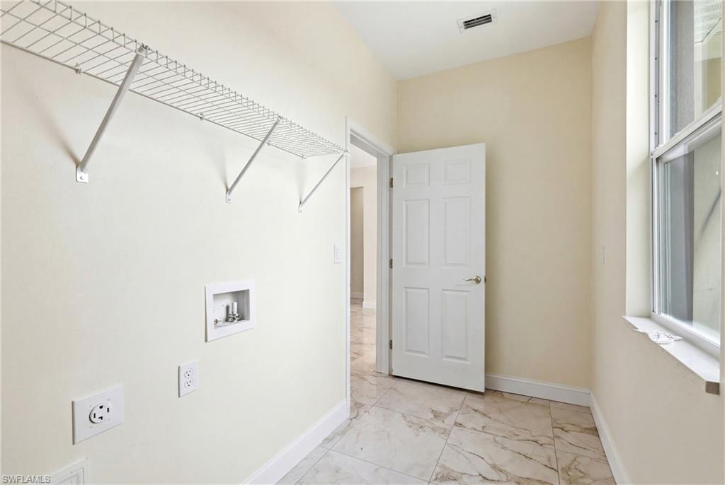 Utility room featuring tile flooring, a window, wire shelving, and a six-panel door