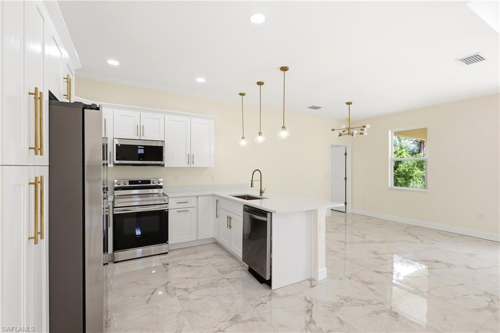Kitchen featuring white cabinetry, stainless steel appliances, a center island with sink, pendant lighting, and large format marble-look tile flooring