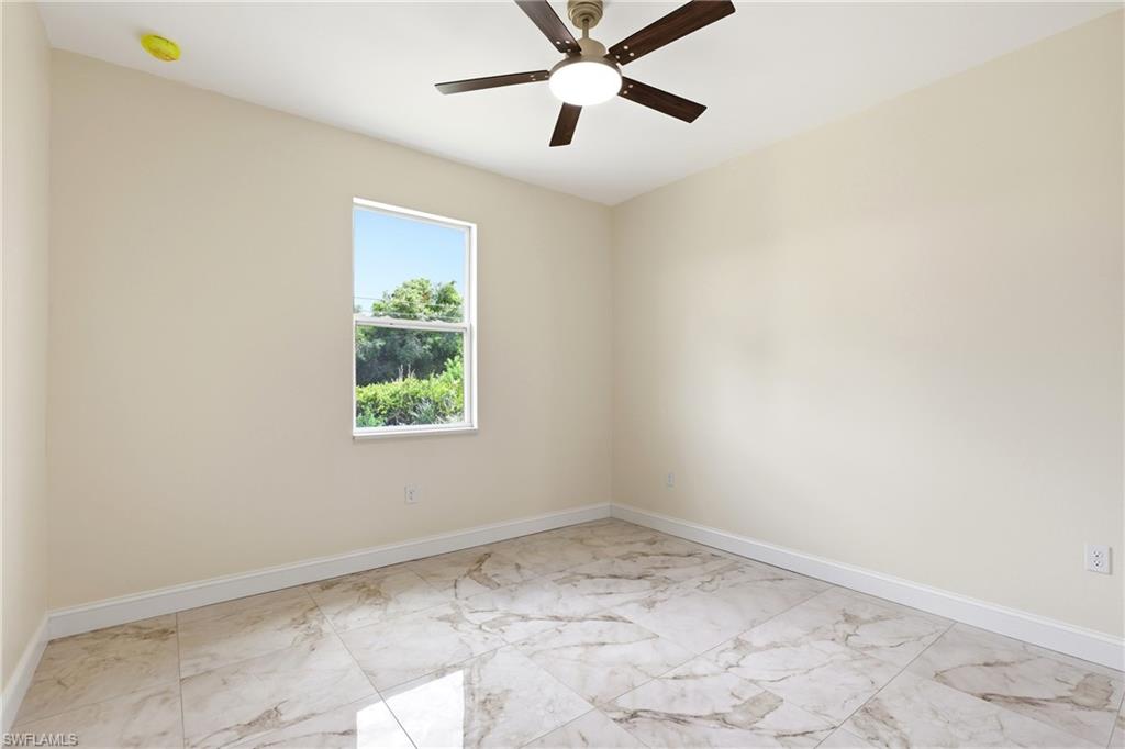 Spacious room featuring light-toned walls, tile flooring, and a ceiling fan