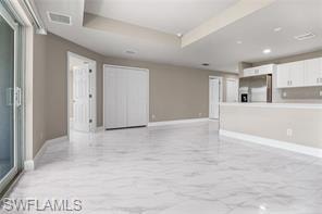 Unfurnished living room with light marble finish floors and a raised ceiling