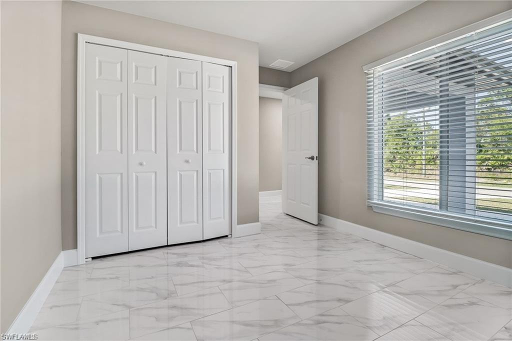 Unfurnished bedroom featuring light marble finish floors and a closet