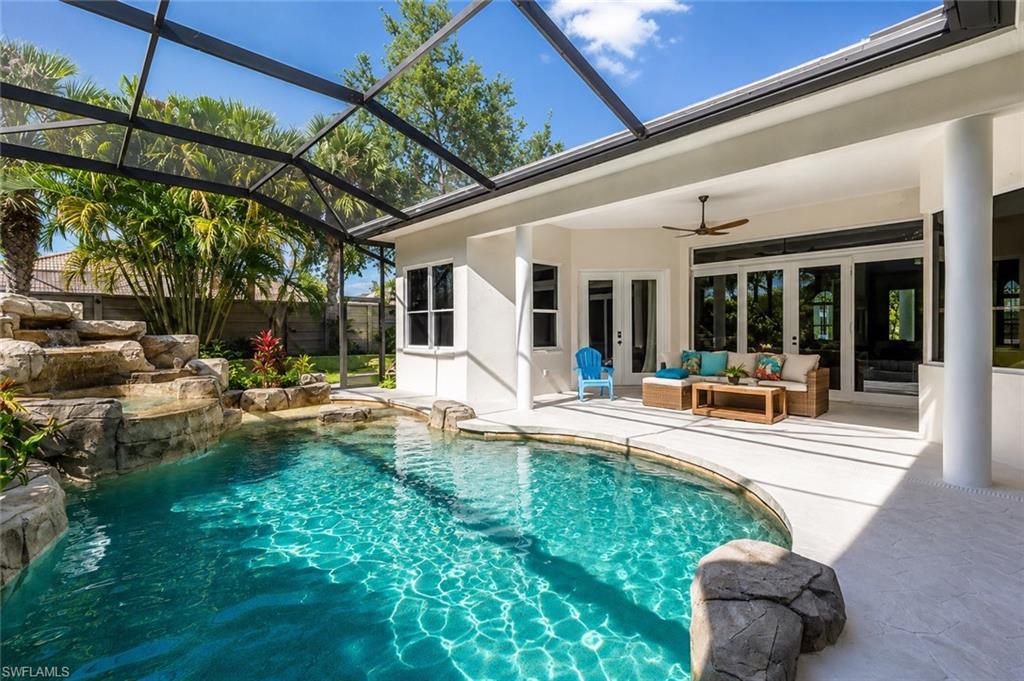 Screened-in outdoor living space with a swimming pool featuring a rock waterfall