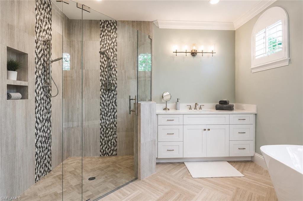 Glass-enclosed shower with decorative tile accents, a built-in niche, and dual shower heads