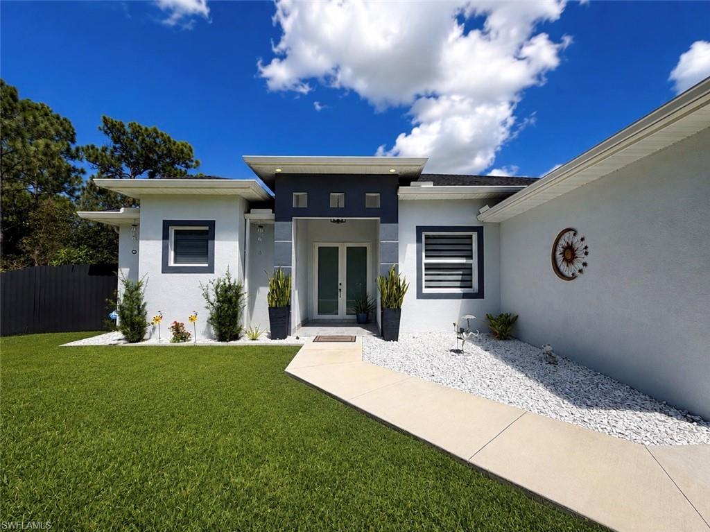 Contemporary exterior with a smooth stucco finish, double entry doors, a concrete pathway, and decorative white rock landscaping