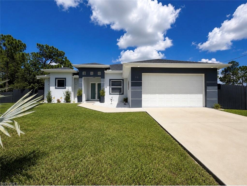 Modern exterior with a white and gray facade, a white garage door, a concrete driveway, and a manicured lawn