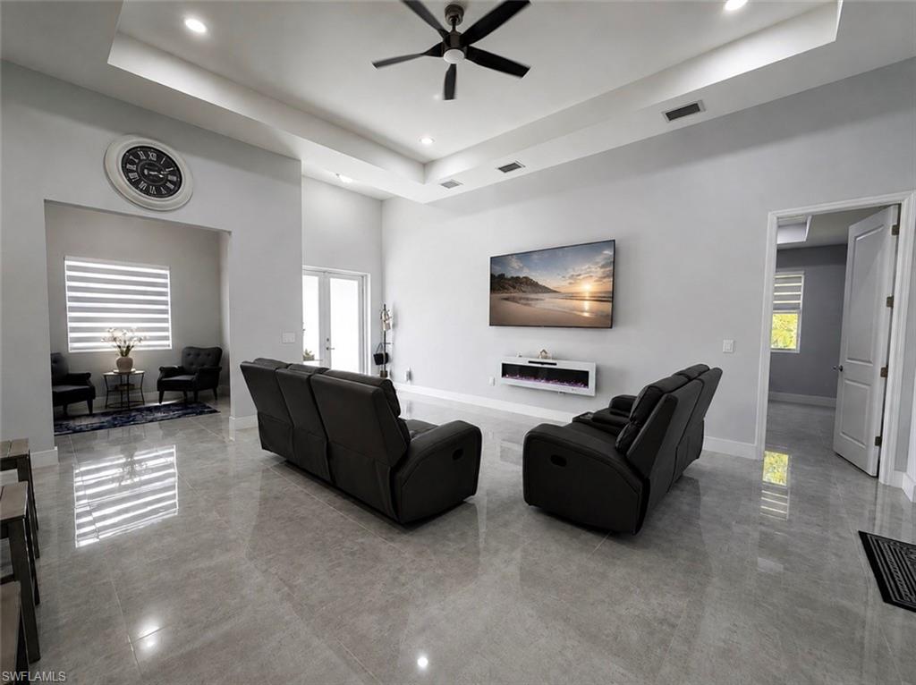 Recessed lighting illuminating a tray ceiling, ceiling fan, and large format polished tile flooring