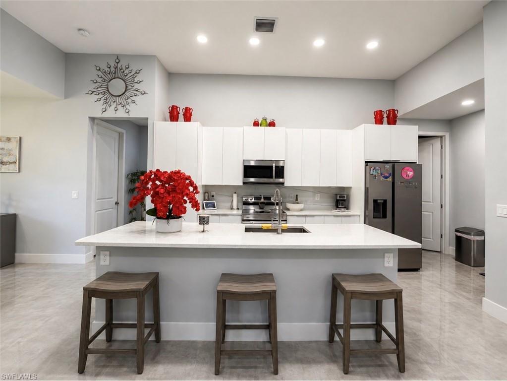 Kitchen with an integrated island, white cabinetry, stainless steel appliances, and wood-finish flooring