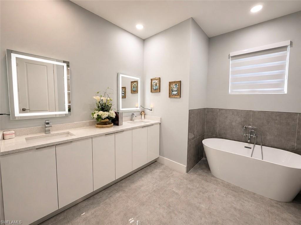 Dual illuminated vanity mirrors over a long double vanity with integrated sinks and light-toned countertops