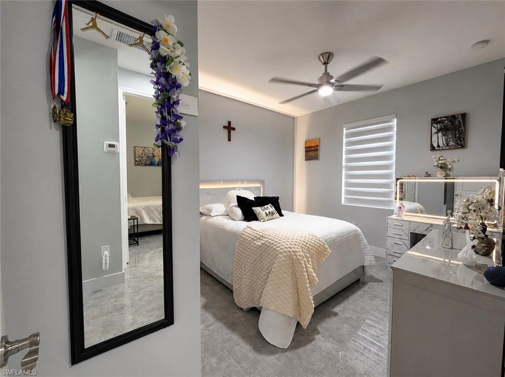 Recessed ceiling lighting, ceiling fan, window with horizontal blinds, light wood-finish flooring, and a mirrored vanity with integrated lighting